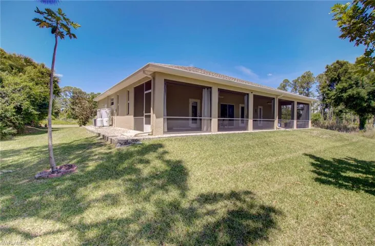 Rear view of property featuring a sunroom and a lawn