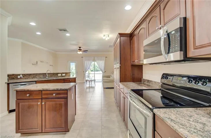 Kitchen featuring a kitchen island, stainless steel appliances, ceiling fan, sink, and light tile floors