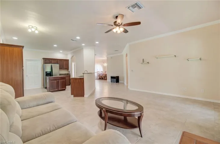 Living room with ceiling fan, crown molding, and light tile flooring