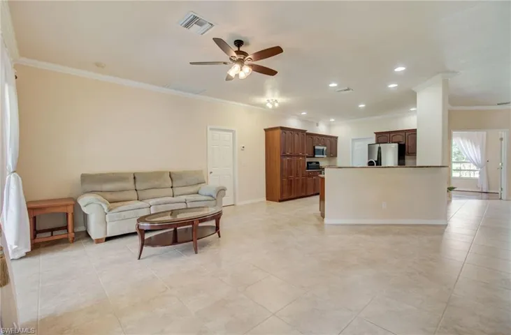 Tiled living room with crown molding and ceiling fan