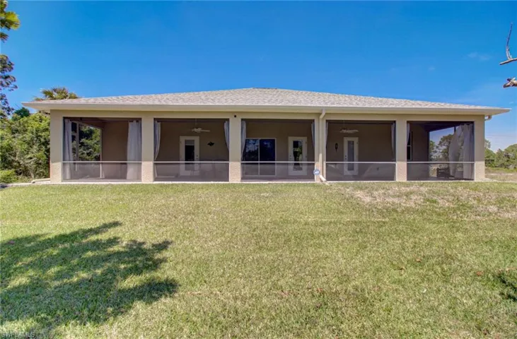 Rear view of property with a yard and ceiling fan