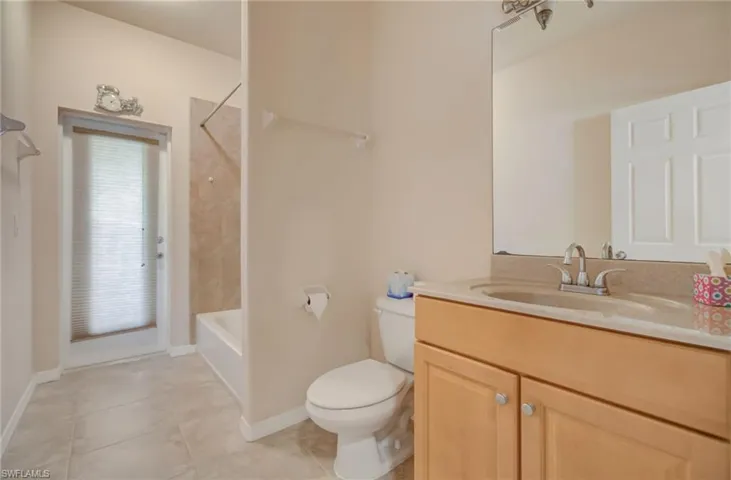Full bathroom featuring tile flooring, vanity, toilet, and tiled shower / bath combo