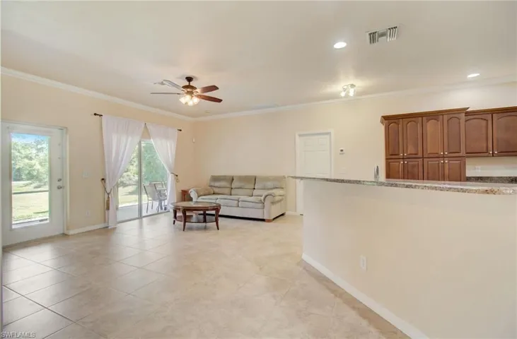 Tiled living room with crown molding and ceiling fan