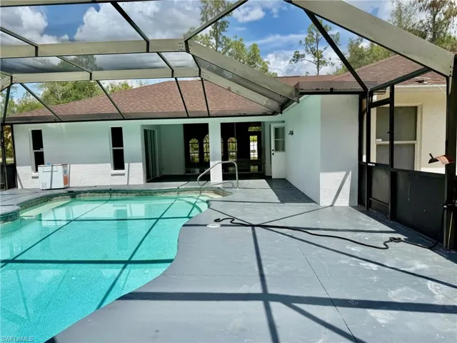 Combined pool / hot tub featuring a sunroom, a patio area, and a lanai
