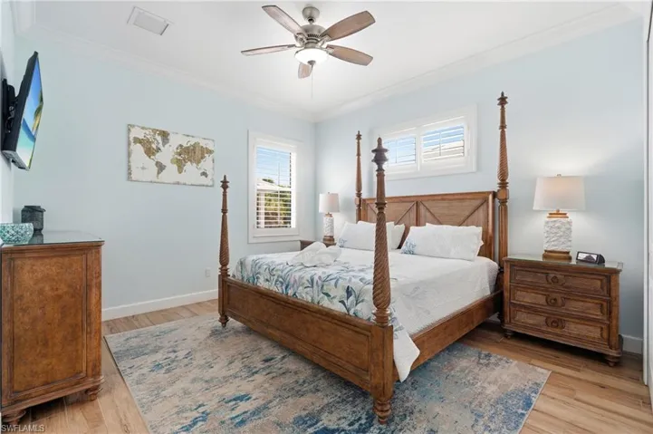 Wood-finish flooring, crown molding, ceiling fan with integrated lighting, and window with plantation shutters - Virtually Edited Image