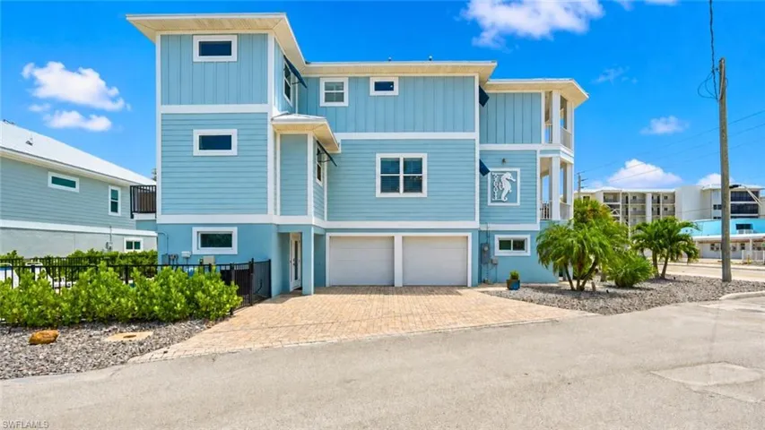 Multi-story coastal residence featuring a metal roof, multiple balconies, and an integrated two-car garage - Virtually Edited Image