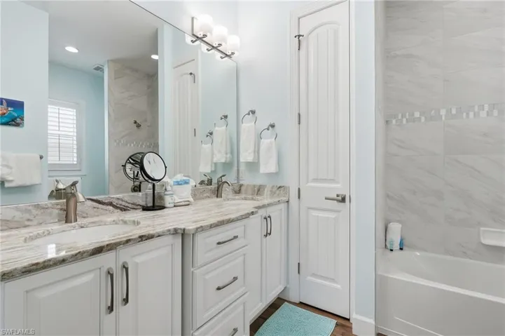 Dual vanity with stone countertop, white cabinetry, and brushed nickel hardware - Virtually Edited Image