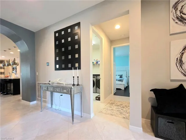 Hall featuring arched walkways, recessed lighting, and washer and clothes dryer