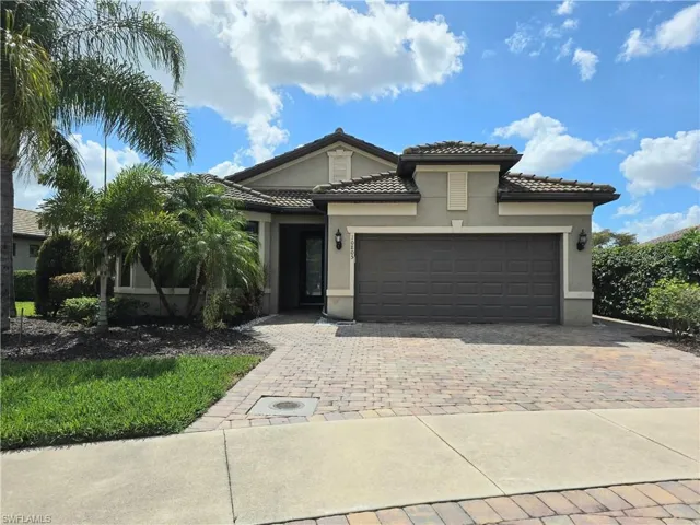 View of front facade featuring an attached garage, stucco siding, decorative driveway, and a tile roof