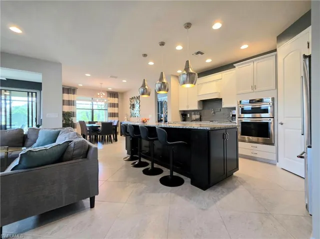 Kitchen featuring a center island with sink, open floor plan, stainless steel appliances, a breakfast bar, and pendant lighting