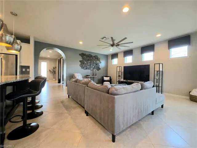 Living area with arched walkways, a ceiling fan, recessed lighting, and light tile patterned floors