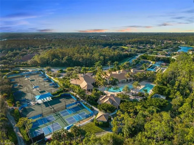 Aerial view at dusk of a wooded view and view of pool area