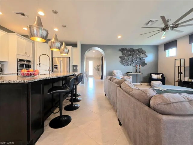Living room featuring arched walkways, light tile patterned floors, recessed lighting, and ceiling fan
