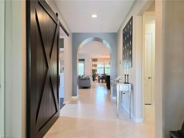 Hallway featuring a barn door, arched walkways, recessed lighting, and light tile patterned floors