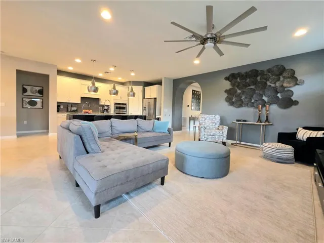 Living area with arched walkways, ceiling fan, recessed lighting, and light tile patterned flooring