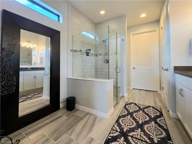 Bathroom with vanity, a stall shower, and wood tiled floors