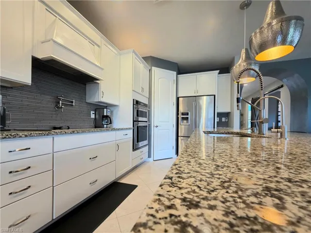 Kitchen featuring white cabinetry, stainless steel appliances, and light stone countertops