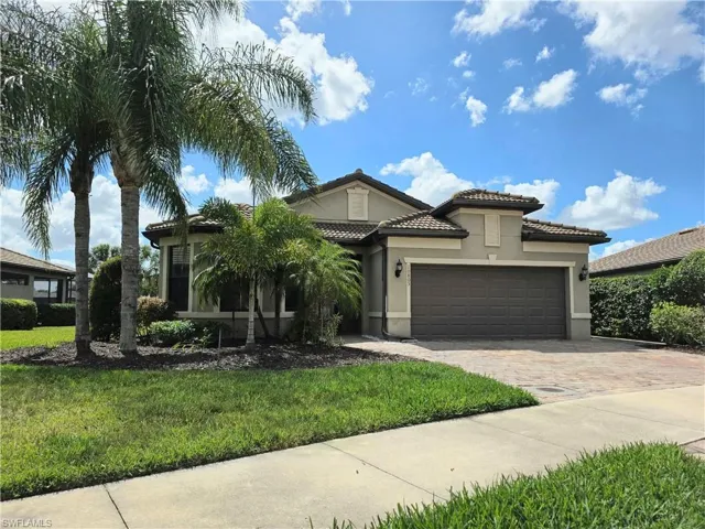 Mediterranean / spanish home featuring stucco siding, an attached garage, driveway, a front yard, and a tile roof