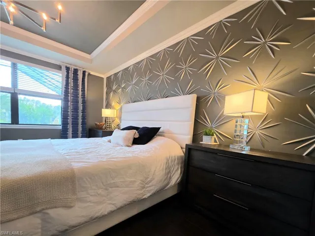 Bedroom featuring ornamental molding, wallpapered walls, and an accent wall