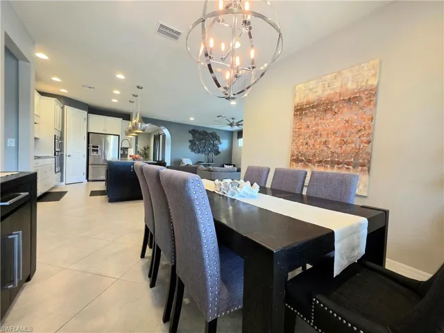 Dining area with arched walkways, a chandelier, and light tile patterned floors