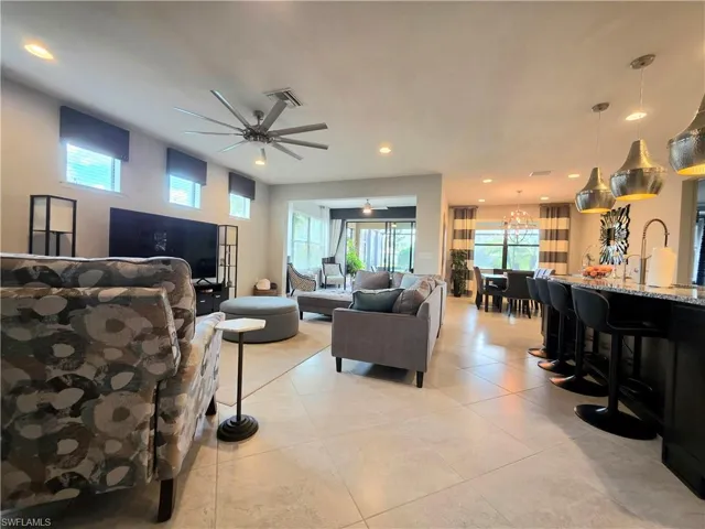 Living area with a ceiling fan, light tile patterned flooring, and recessed lighting