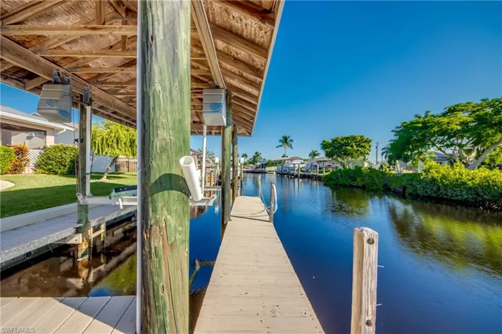 Wrap around dock with metal roof covered boat lift and view down main canal to the Caloosahatchee Intracoastal Waterway and on to the Gulf!