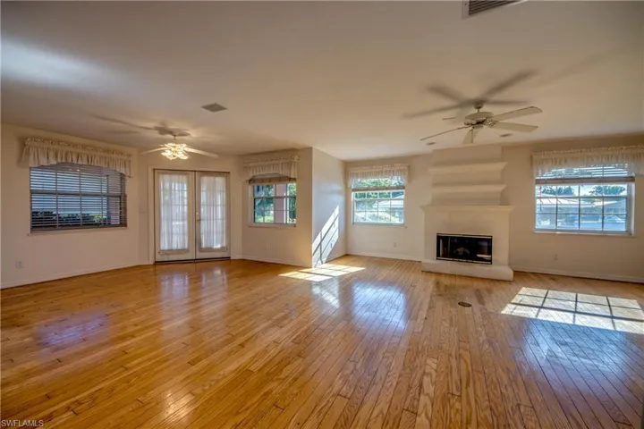 Great room and Fireplace. French doors to left lead to the Covered and Screened Lanai. Six windows and 2 sets of french doors create a light filled great room.