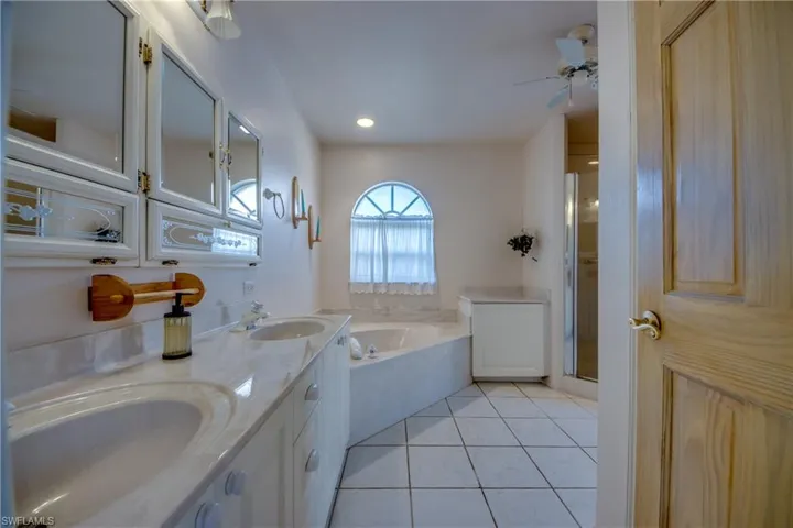 Primary en-suite bathroom is spacious and features double sinks and a large vanity, Soaking tub, linen closet, separate water closet and a walk-in shower. There is French door leading to the Private courtyard .