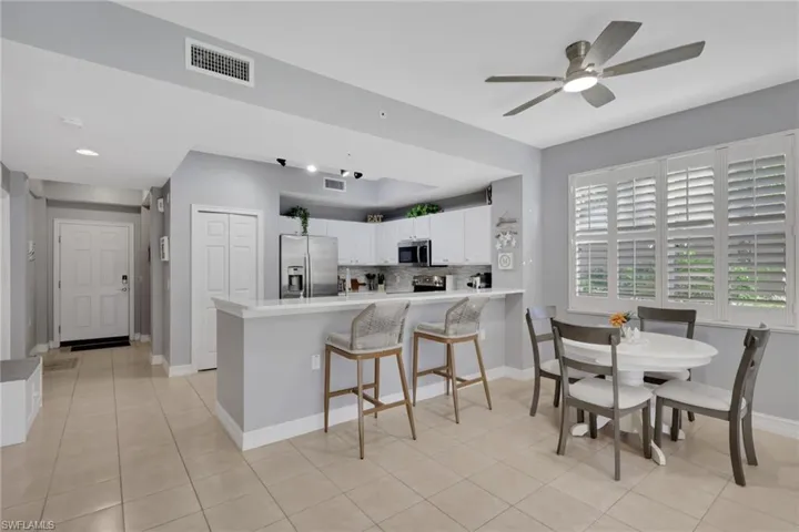Kitchen with appliances with stainless steel finishes, white cabinetry, light countertops, a peninsula, and a breakfast bar
