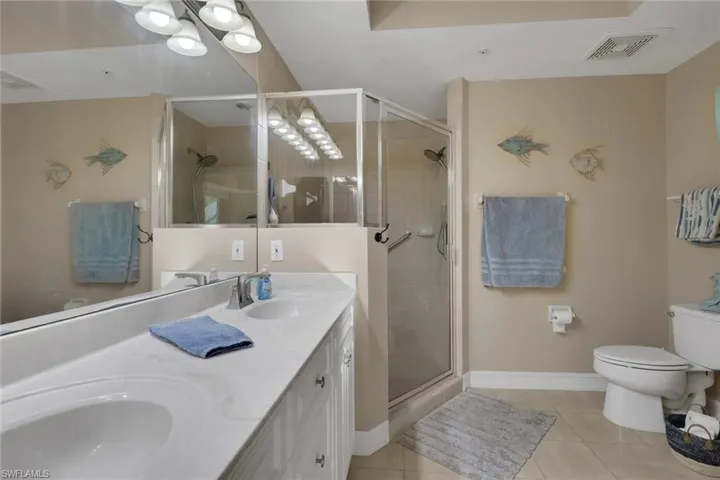 Bathroom featuring double vanity, a stall shower, and light tile patterned floors