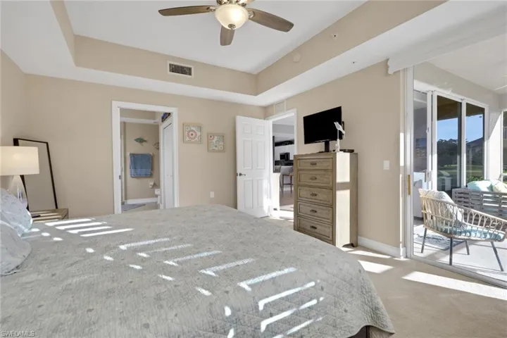 Bedroom with access to outside, a raised ceiling, light carpet, a ceiling fan, and ensuite bath