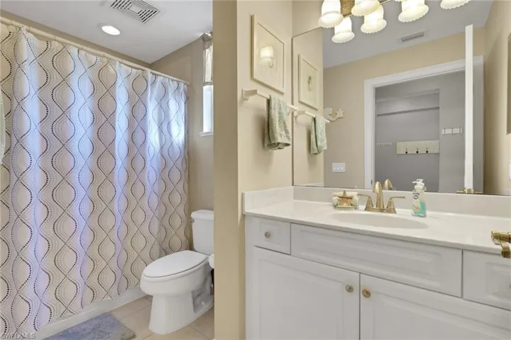 Bathroom with curtained shower, vanity, light tile patterned flooring, and a chandelier
