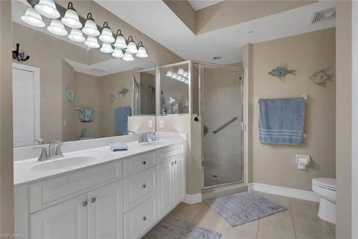 Full bath featuring double vanity, a stall shower, and light tile patterned floors
