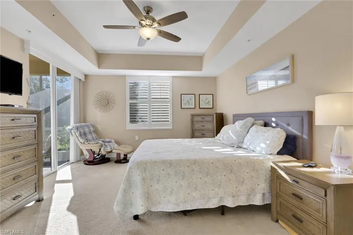 Bedroom with access to exterior, multiple windows, light colored carpet, and a ceiling fan