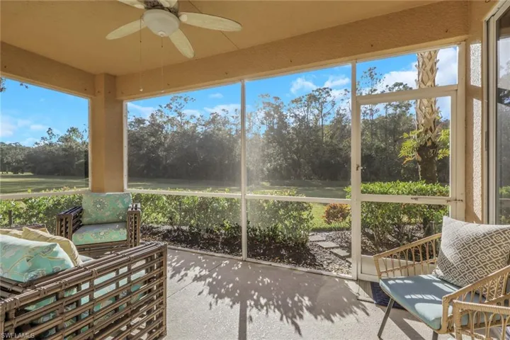 Sunroom / solarium featuring view of scattered trees and a ceiling fan