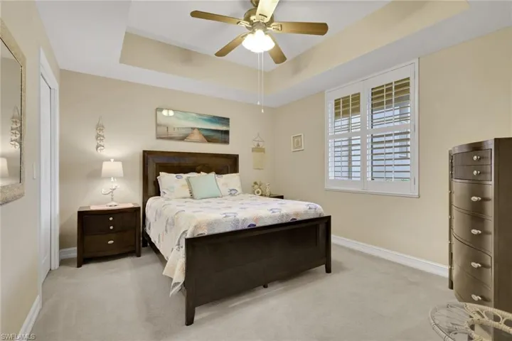 Carpeted bedroom featuring a raised ceiling and ceiling fan