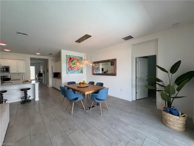 Open-concept dining area featuring a wood-finish table and a contemporary rectangular pendant light fixture