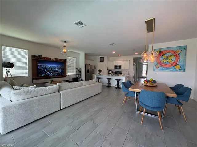 Open-concept living space featuring wood-finish flooring, recessed lighting, and a modern dining light fixture