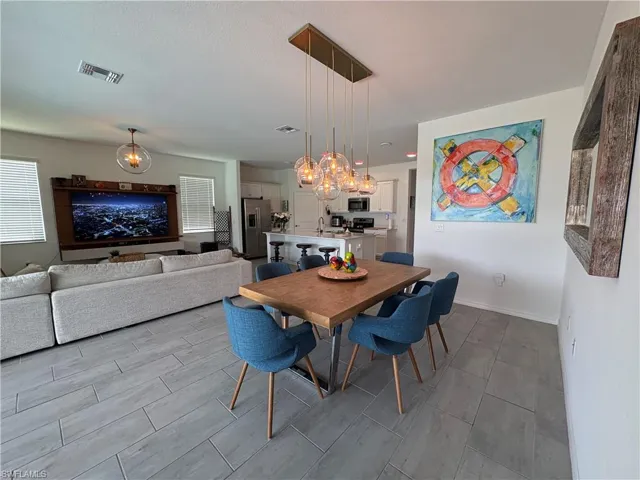 Open concept living area featuring wood-finish flooring, a linear pendant light fixture, recessed lighting, and white baseboards