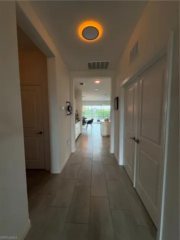 Hallway featuring plank-style tile flooring, white baseboards, and a contemporary ceiling light fixture