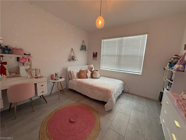 Bedroom featuring light-toned flooring, white walls, and a single window with horizontal blinds