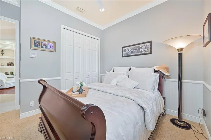 Bedroom with a closet, ornamental molding, light colored carpet, and ceiling fan