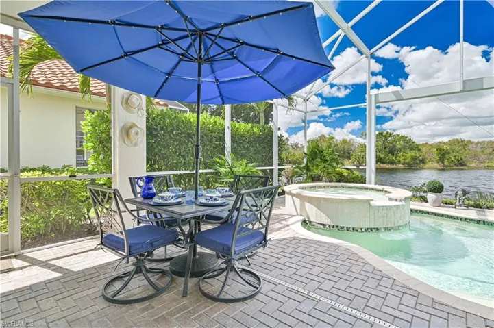 View of patio featuring a pool with connected hot tub, a lanai, and outdoor dining area