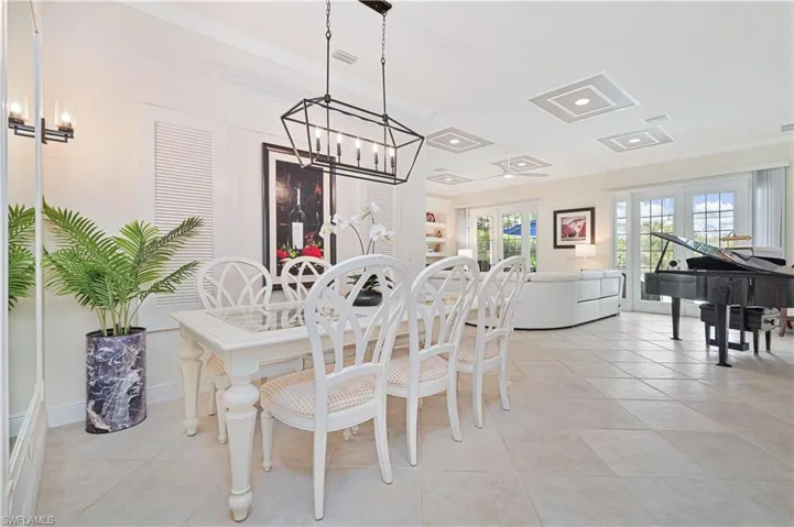 Dining area featuring ornamental molding, light tile patterned floors, a chandelier, and french doors
