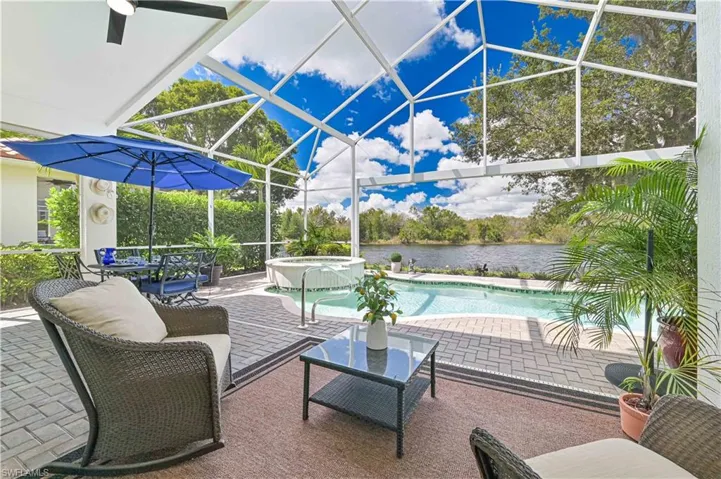 View of patio / terrace featuring a sunroom, a lanai, a pool with connected hot tub, and a water view