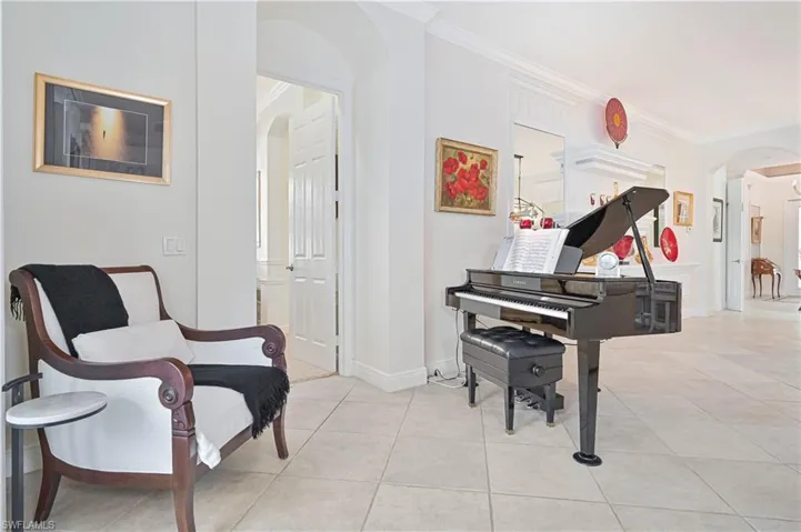 Living area with arched walkways, ornamental molding, and light tile patterned floors