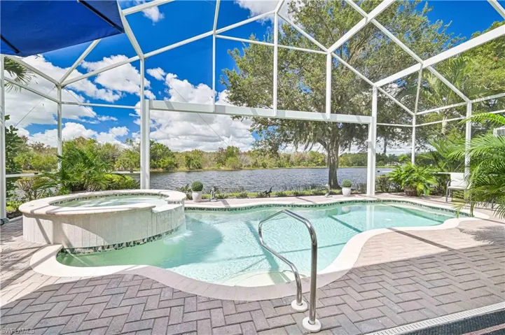 View of swimming pool featuring a sunroom, glass enclosure, a pool with connected hot tub, a water view, and a patio