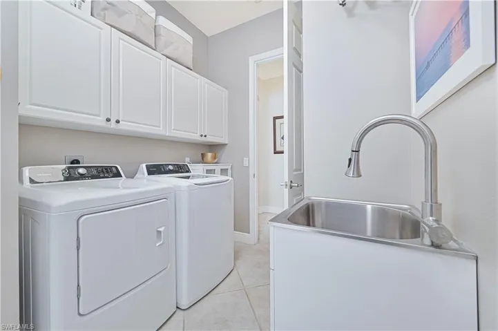 Laundry area with cabinet space, light tile patterned flooring, and washer and dryer
