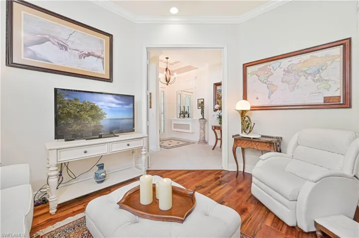 Living room featuring crown molding, a chandelier, and wood finished floors