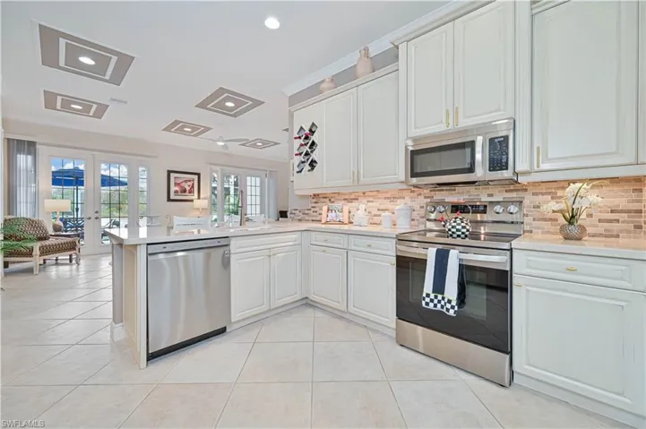 Kitchen with stainless steel appliances, french doors, light tile patterned flooring, recessed lighting, and backsplash